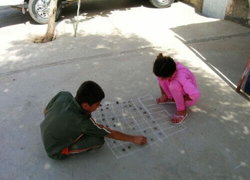 Children playing a game made out of stones and chalk.